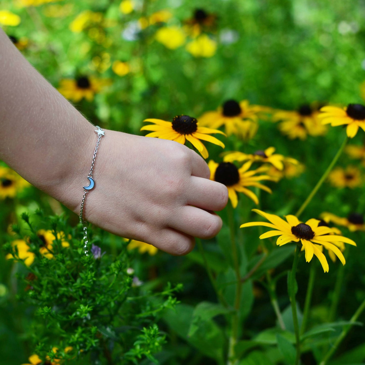 Girl picking flowers and wearing Sterling Silver Celestial Blue Moon Star Yellow Sun with Enamel Extendable Chain Bracelet with Heart Charm